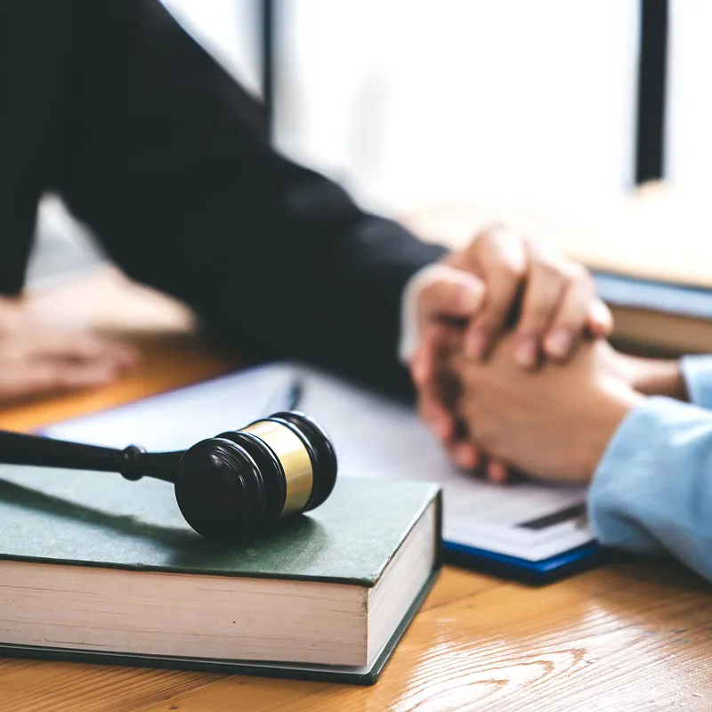 Gavel resting on a law book while an attorney meets with a client