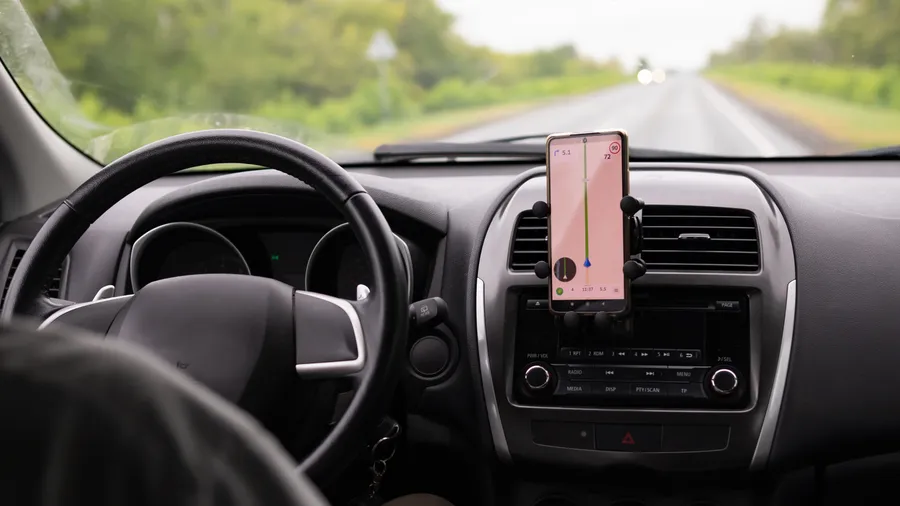A phone running turn-by-turn navigation mounted on a car dashboard
