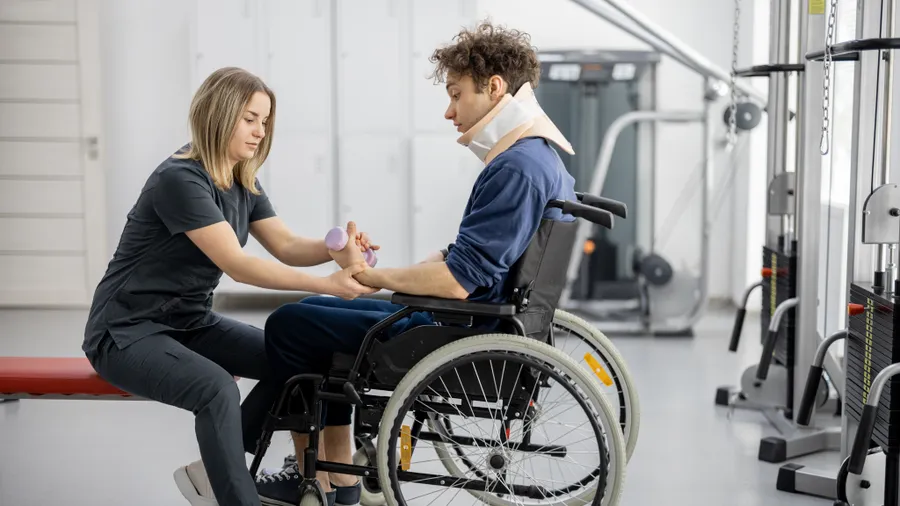 A physical therapist working through an exercise with a man in a wheelchair