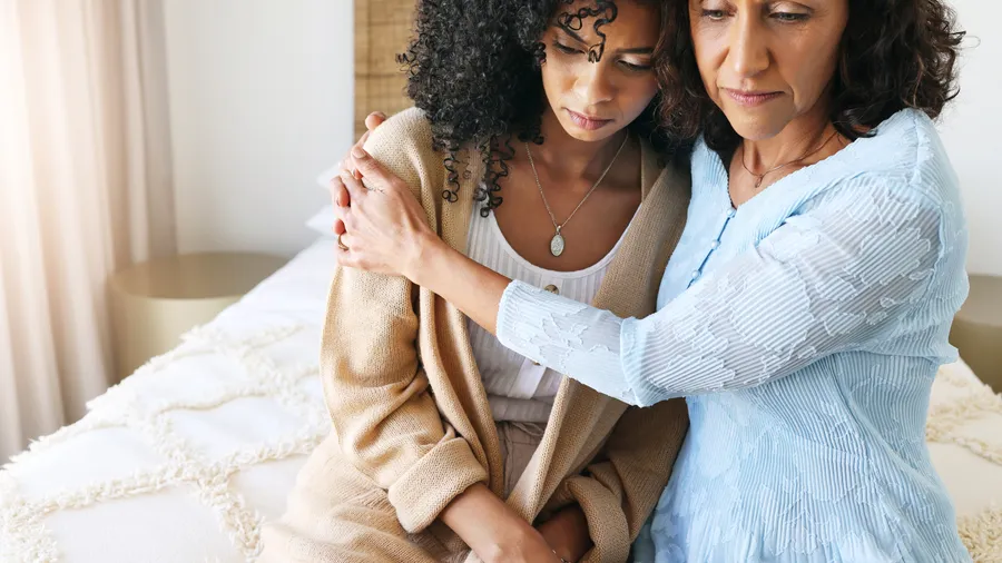 One woman comforting another with an embrace indoors