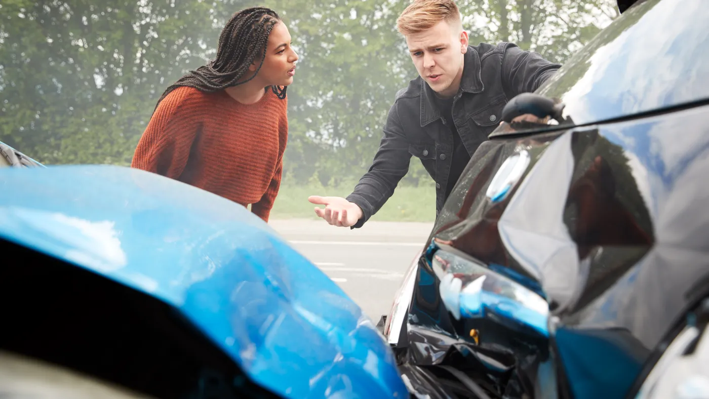 Two people examining damage after an accident